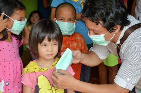 Relawan Astra Membantu seorang anak Memasang masker