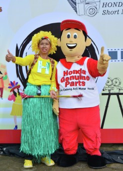 Seorang peserta kostum berfoto dengan maskot Honda