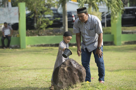 ayah dan anak yang berziarah ke kuburan massal Tsunami Aceh